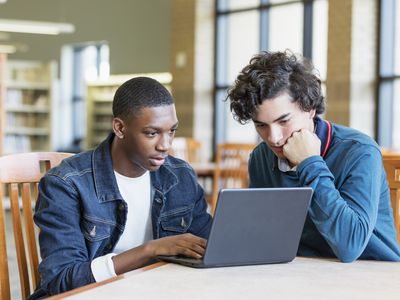 两位少年男孩一起学习,坐在图书馆表前